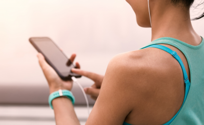 Female runner holding phone and listening to music with headphones on.
