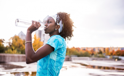 Woman drinking water out of a water bottle outside