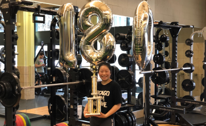 Emily With Balloons and A Trophy standing in front of a squat rack