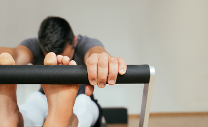 Man stretching his hamstrings on a Pilates reformer